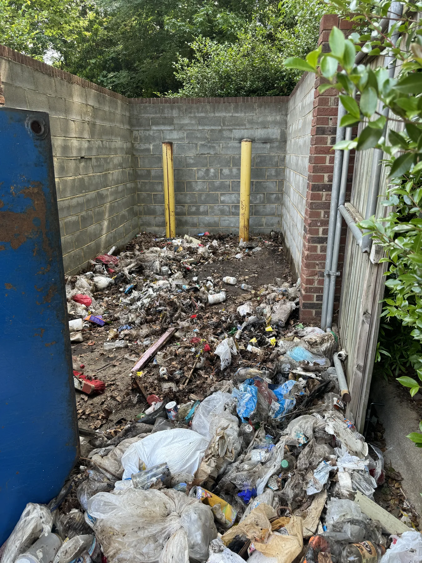 Overflowing dumpster corral before A-Z cleanup